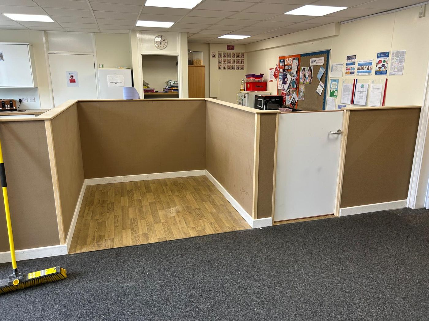 L-shaped reception counter with a door, framed and boarded in an office, before decorating