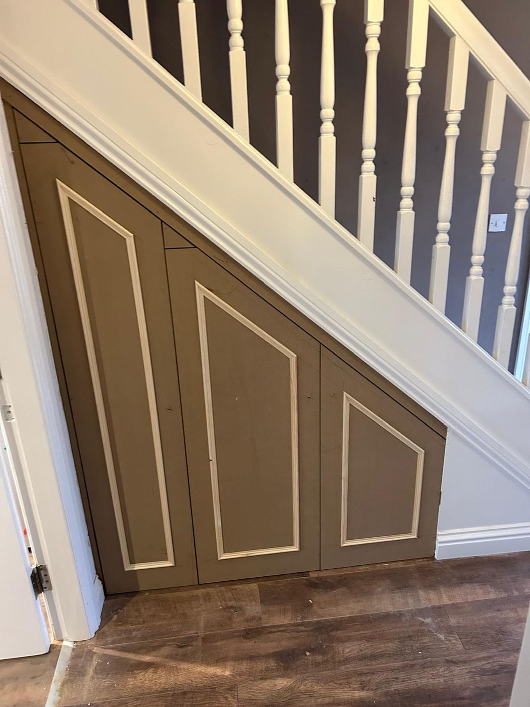 Three cupboard doors with mouldings shaped to the underside of a staircase, before painting